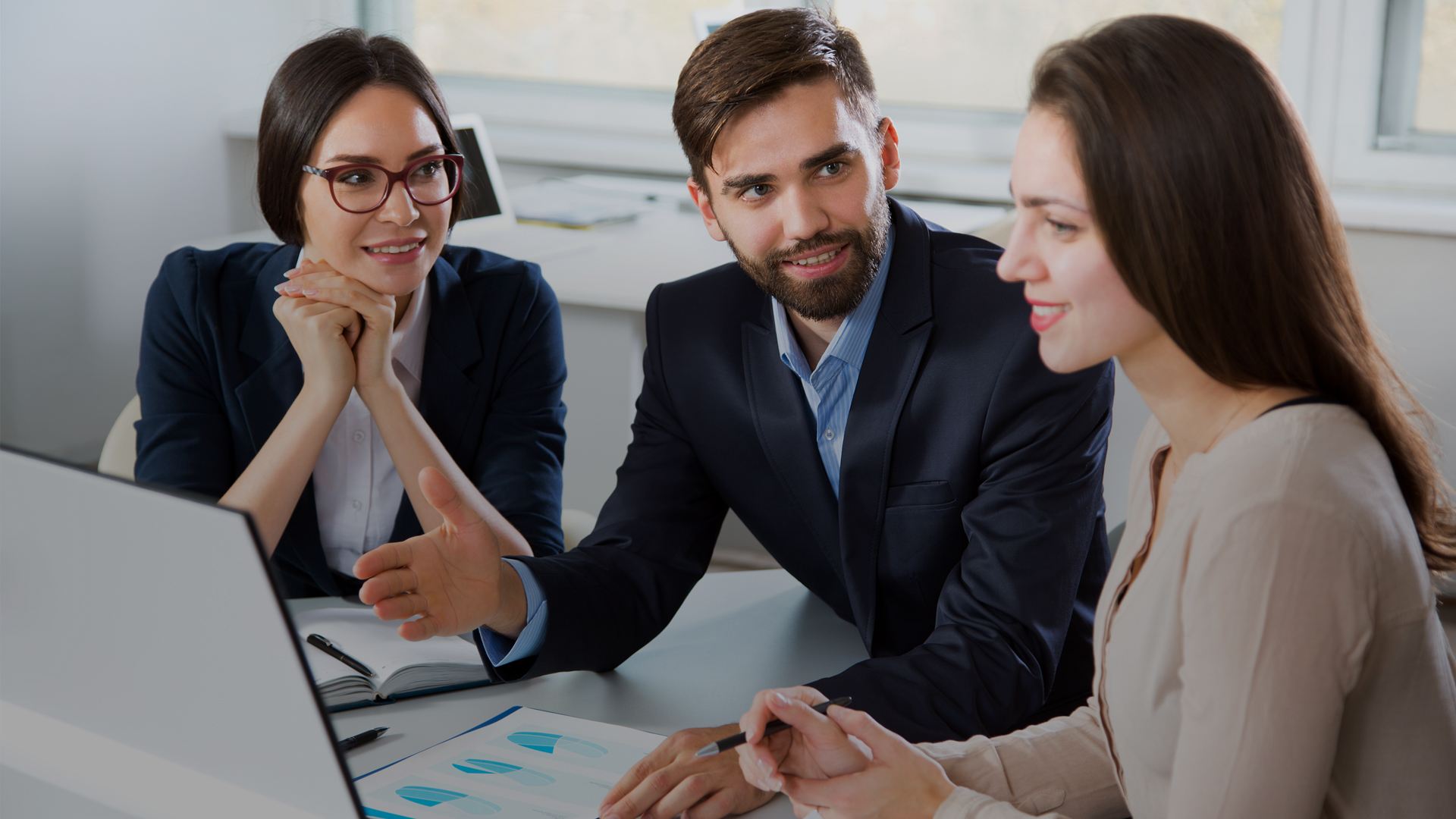 Business professional reviewing financial documents and making notes at a desk.