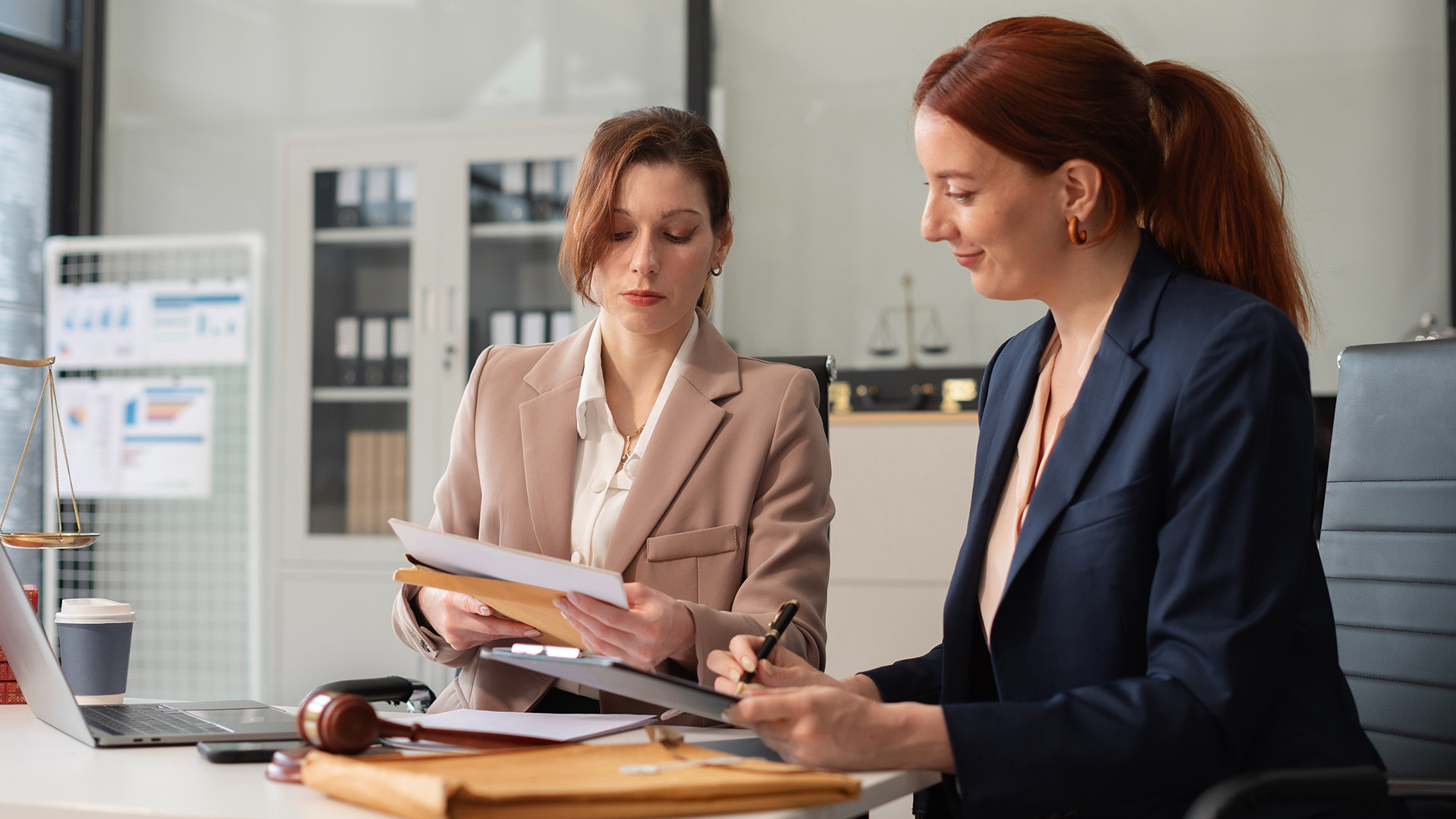 Two businesswomen seated at a desk, discussing documents, reflecting commitment to accountability and ESG management.