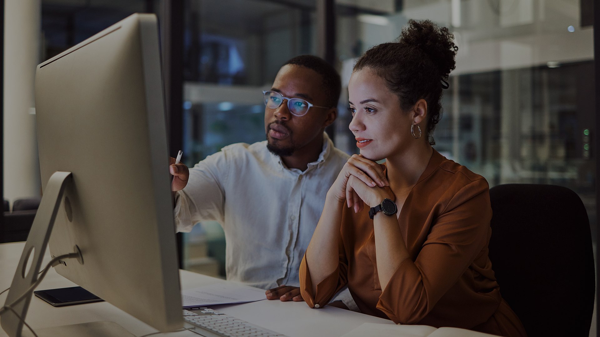Two cybersecurity professionals discussing the impact of generative AI in enhancing their posture in a workplace.