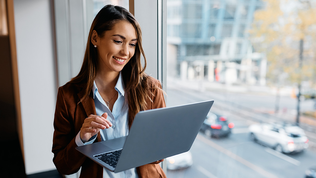 A girl is working on her laptop and smiling to see her data results.