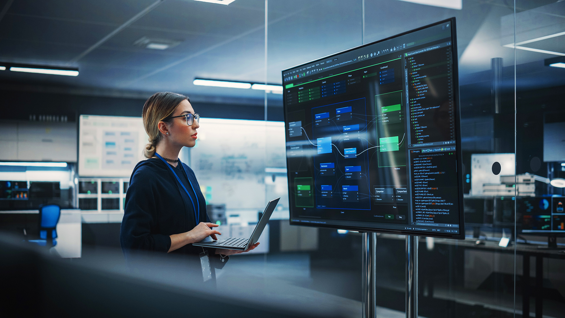 A woman with a laptop analyzes data on a large screen, evaluating AI-enabled and AI-native customer support outsourcing solutions.