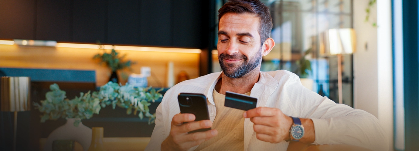  Millennial man standing outside checking his account balance on his cell phone.