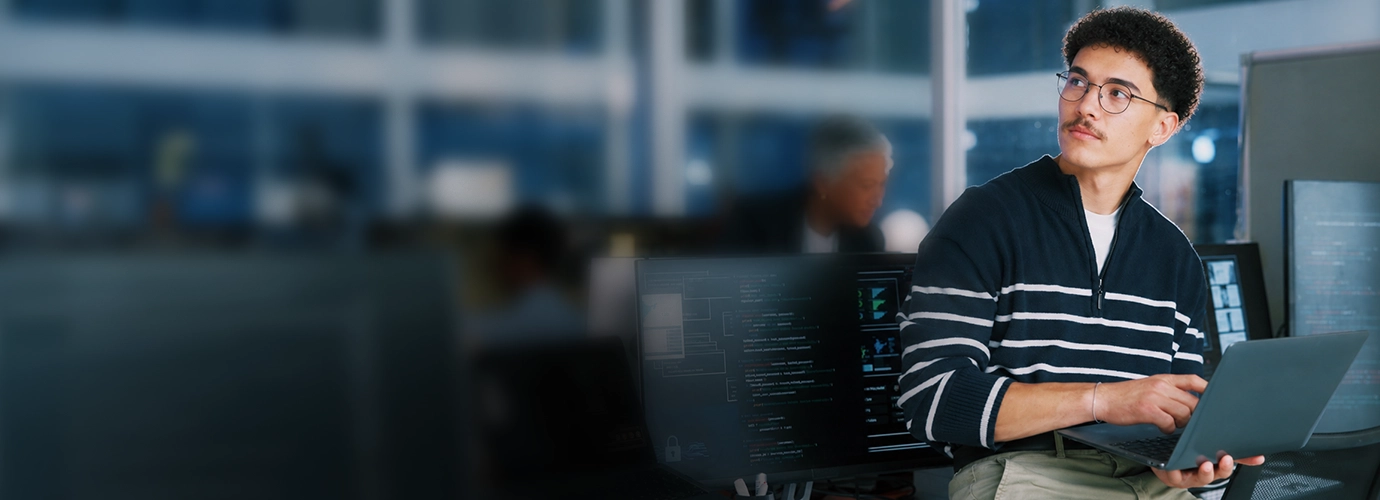 An IT professional using a laptop to monitor cybersecurity operations.